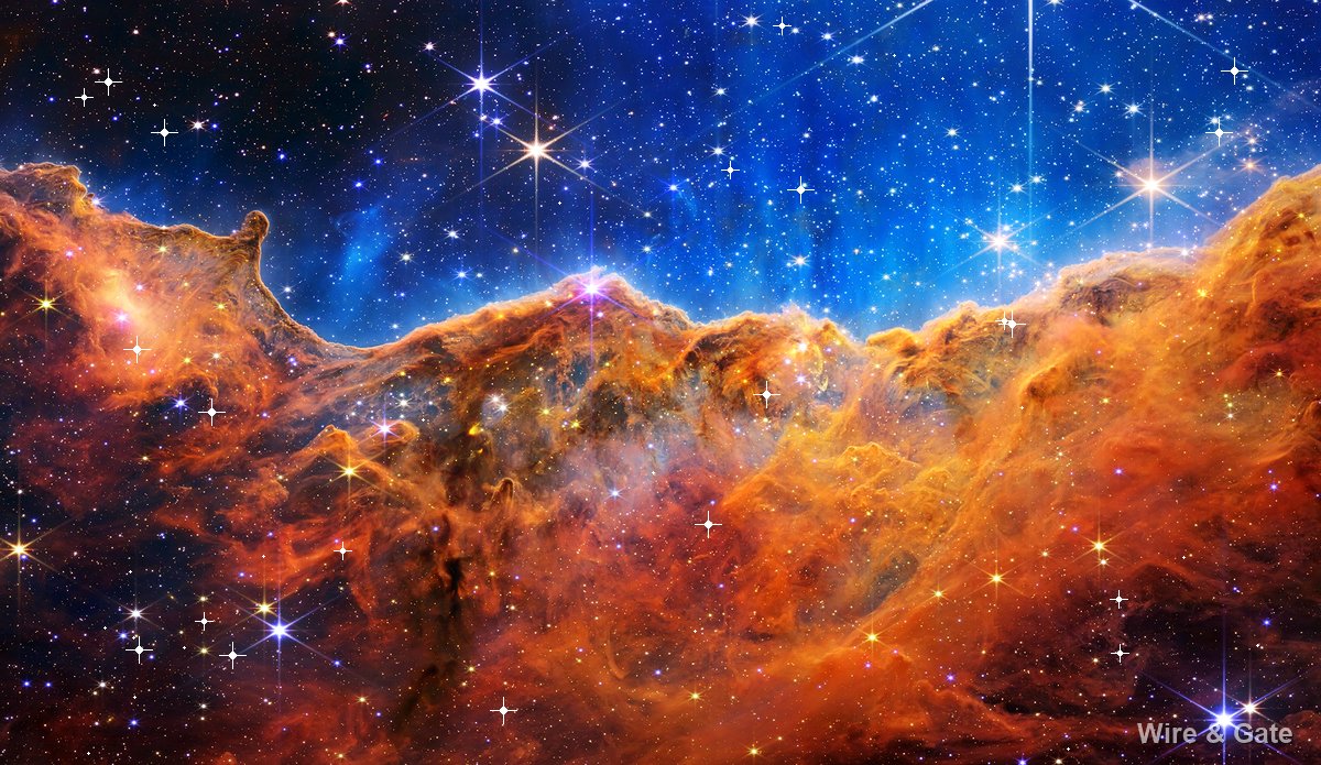A cliff of orange gas under a blue sky scattered with stars